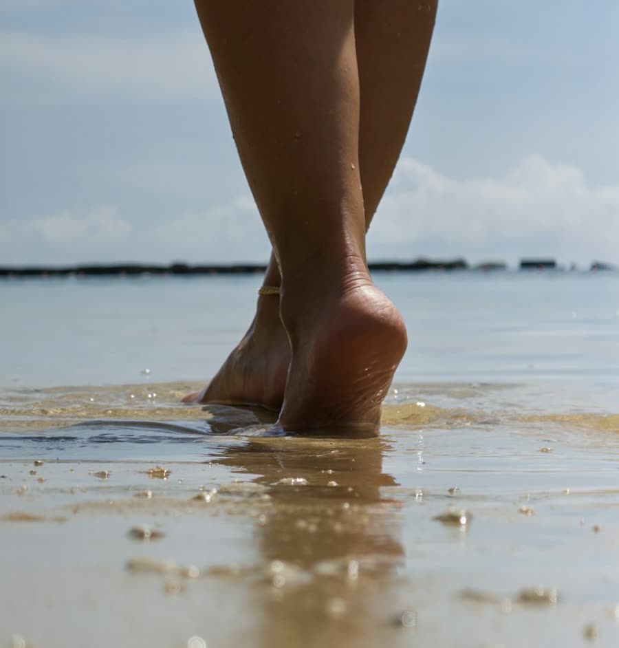 Bare feet in shallow water at the edge of the beach