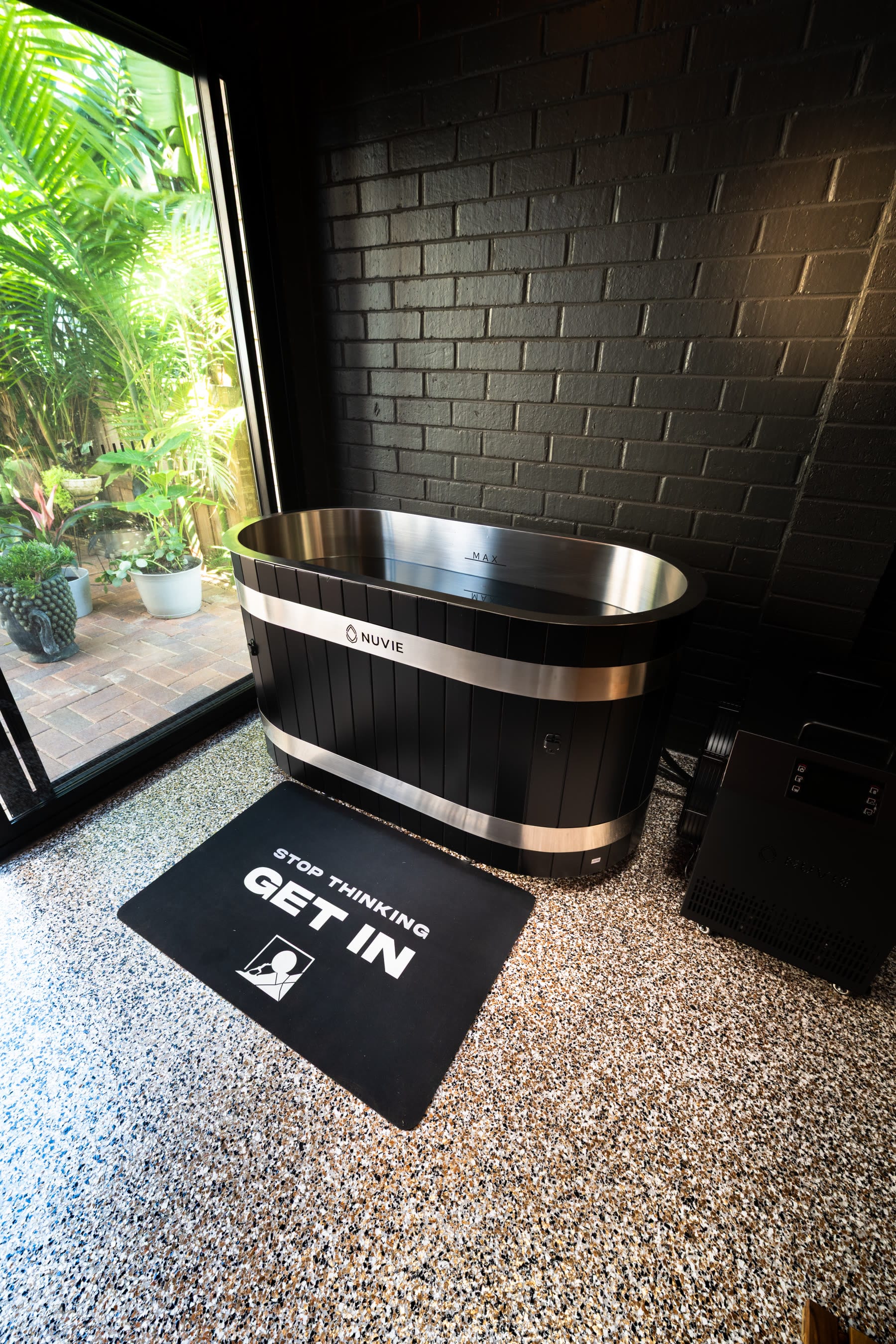 The black timber ice bath beside the garden window